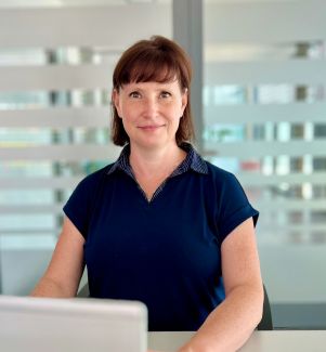 Frau sitzt am Schreibtisch und lächelt