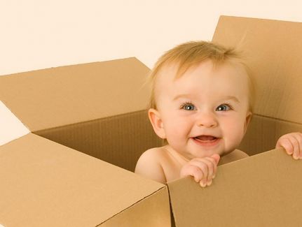 Ein Baby schaut aus einem Pappkarton raus